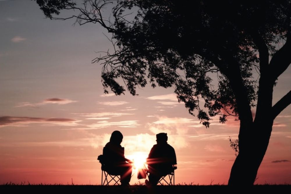 twee mensen bij boom met zonsondergang